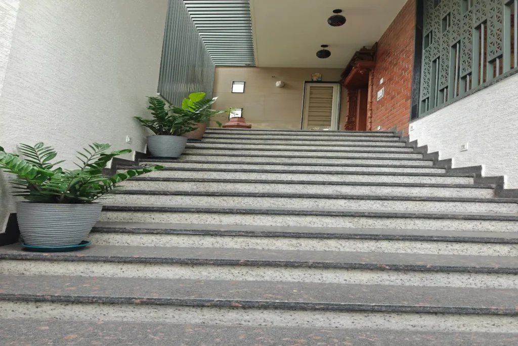 Elegant staircase design at Arohana Rising residence with greenery and architectural details.